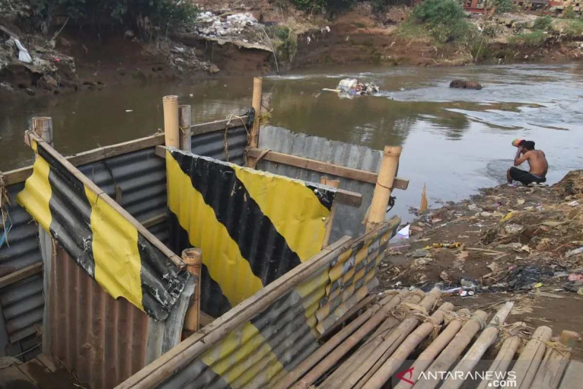 Seorang warga mandi di dekat bilik kakus atau jamban di kawasan Kampung Melayu, Jakarta, Rabu (16/10/2019). ANTARA FOTO/Indrianto Eko Suwarso/foc.
